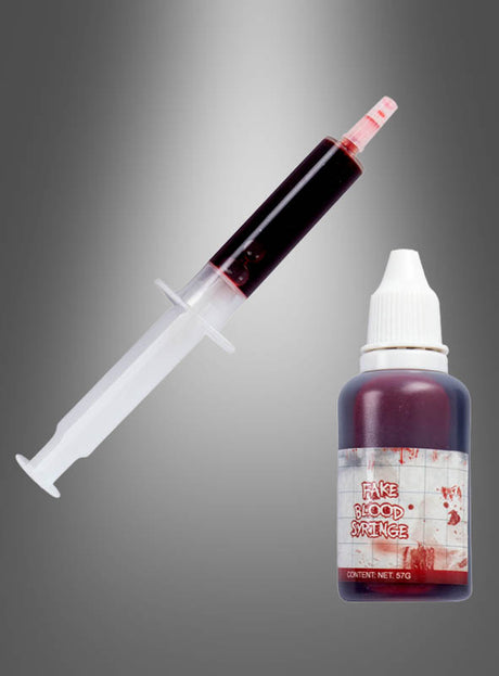 Eine mit Kunstblut gefüllte Spritze ist neben einer kleinen Flasche mit der Aufschrift „Fake Blood Syringe“ vor einem grauen Farbverlaufshintergrund platziert – ideal, um Ihrer Halloween-Dekoration einen zusätzlichen Hauch von Realismus zu verleihen.