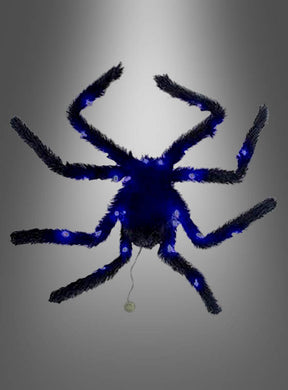 Eine blaue, flauschige Spinne mit acht Beinen und einem hinter ihr herziehenden Faden ist vor einem grauen Hintergrund mit Farbverlauf abgebildet – perfekt als auffällige Halloween-Dekoration, die sich ideal mit der „Großen schwarzen Spinne 65 cm mit Licht“ kombinieren lässt.