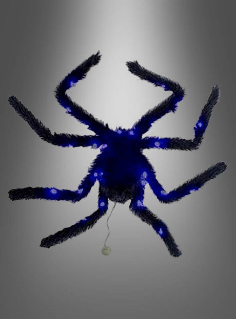Eine blaue, flauschige Spinne mit acht Beinen und einem hinter ihr herziehenden Faden ist vor einem grauen Hintergrund mit Farbverlauf abgebildet – perfekt als auffällige Halloween-Dekoration, die sich ideal mit der „Großen schwarzen Spinne 65 cm mit Licht“ kombinieren lässt.