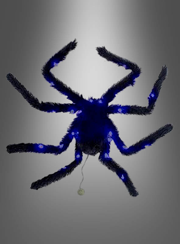 Eine blaue, flauschige Spinne mit acht Beinen und einem hinter ihr herziehenden Faden ist vor einem grauen Hintergrund mit Farbverlauf abgebildet – perfekt als auffällige Halloween-Dekoration, die sich ideal mit der „Großen schwarzen Spinne 65 cm mit Licht“ kombinieren lässt.