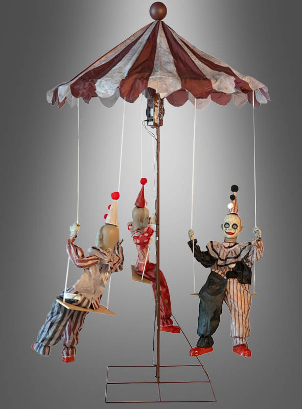 Das „Clown Trio Karussell“-Halloween-Dekostück (130 x 220 cm) zeigt drei Clown-Puppen in gestreiften Kostümen und Hüten, die unter einem rot-weißen Zirkusdach an Schaukeln hängen. Diese auffällige Dekoration, die auf einem metallischen Ständer vor einem grauen Farbverlaufshintergrund steht, eignet sich perfekt, um Ihrer „Halloween Clowns Karussell“-Ausstellung einen gruseligen Touch zu verleihen.