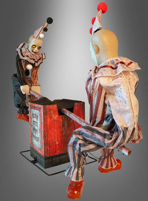 Zwei Figuren der Serie „Wippende Clowns animiert 125x90cm Deko“ in gestreiften Kostümen bedienen eine rot-schwarze Wippe mit der Aufschrift „Clown See Saw Torture“; die animierten Clowns bilden vor einem grauen Hintergrund mit Farbverlauf eine herrlich unheimliche Halloween-Dekoration.