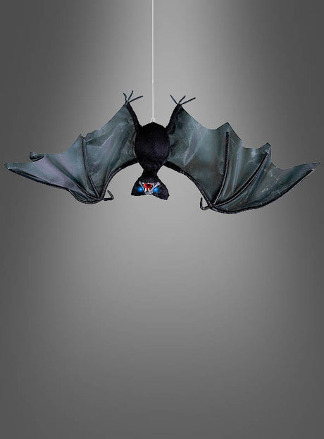 Eine „Animierte Fledermaus 80 cm“ mit ausgebreiteten schwarzen Flügeln hängt kopfüber an einer dünnen Schnur vor einem grauen Hintergrund – perfekt als dezenter und dennoch auffälliger Halloween-Deko-Akzent für Ihre gruselige Kulisse.