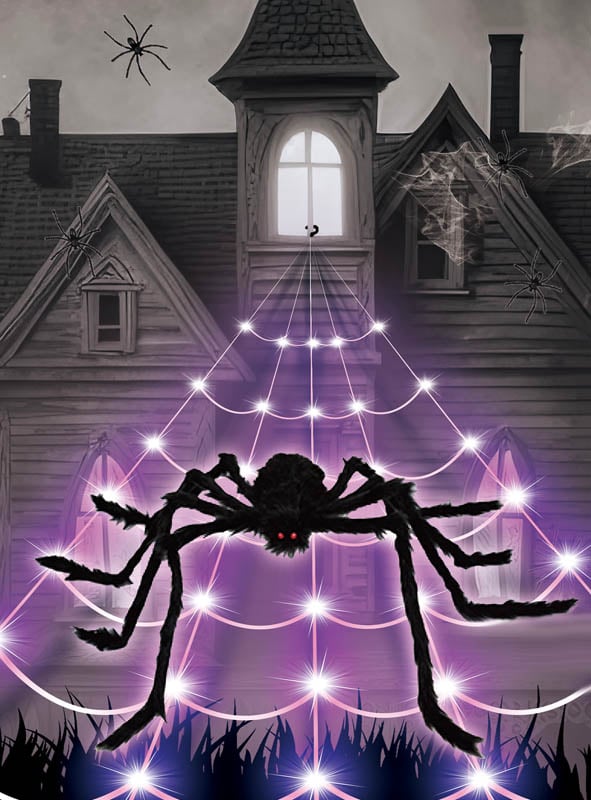 Eine große Spinne mit leuchtend roten Augen sitzt auf dem LED-Spinnennetz (5 Meter mit Spinne) vor einem gruseligen, alten Haus; zusätzliche Spinnen und Spinnennetze schmücken das Gebäude und sorgen so für die perfekte Halloween-Dekoration.
