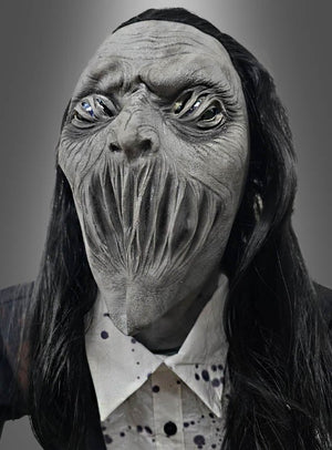 Die Figur trägt eine detailreiche „Gigantischer Zombie 230 cm“-Animatronik-Maske mit verzerrten Gesichtszügen, hohlen Augen und langen vertikalen Schlitzen als Mund und erinnert an einen hoch aufragenden Friedhofsgeist. Mit ihrem langen schwarzen Haar und einem Hemd mit Kragen vermittelt sie den gruseligen Eindruck einer beunruhigenden Halloween-Figur, die zum Leben erweckt wurde.