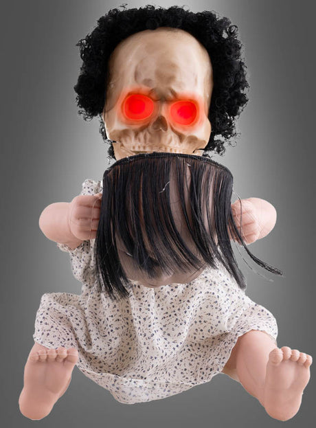 Die 40 cm große, animierte Horrorpuppe mit zwei Gesichtern hat einen Totenkopf, leuchtend rote Augen, lockiges schwarzes Haar mit glattem Pony und trägt ein gemustertes Kleid – vor einem grauen Hintergrund platziert ist sie die perfekte Halloween-Dekoration.