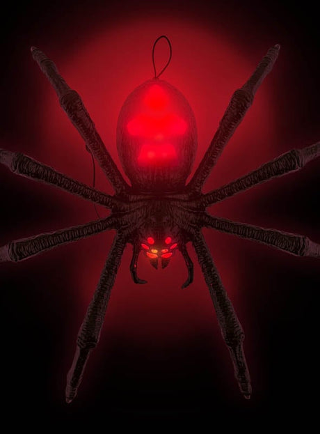 Eine große schwarze „Terror Spinne“ – eine 70 cm große Tarantel mit Licht- und Soundeffekten –, die sich durch leuchtend rote Markierungen auf Körper und Gesicht vor einem dunklen Hintergrund mit rotem Lichteffekt auszeichnet – diese animierte Riesenspinne eignet sich perfekt als gruselige Halloween-Dekoration.