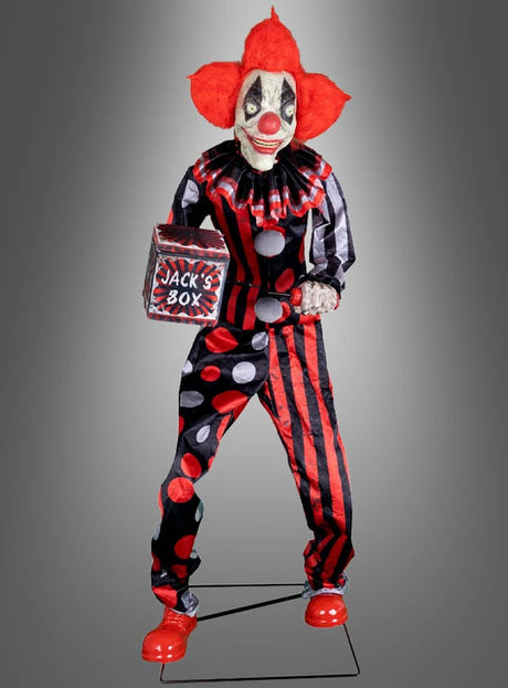 Eine Person in einem rot-schwarzen Clownskostüm mit roten Haaren, die eine Springpuppe in der Hand hält, steht vor einem grauen Hintergrund mit Farbverlauf – perfekt als „Riesige Clown-Figur 175 cm, animiert“ für alle, die nach animierter Halloween-Dekoration mit dem gruseligen Flair eines Horrorclowns oder klassischer Narrenclown-Halloween-Deko suchen.