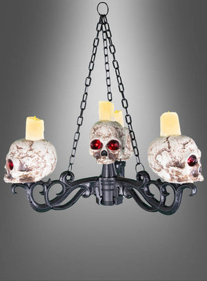 Großer Totenkopf-Kerzenleuchter 155 cm Kronleuchter – ein auffälliger Kronleuchter aus schwarzem Metall mit drei Totenköpfen mit roten Augen und einer verwitterten Optik, die jeweils als Kerzenhalter für gelbe Kerzen dienen. Dieses Stück eignet sich perfekt als Halloween-Kerzenständer und verleiht Ihrem Raum einen gespenstischen Charakter, während der graue Hintergrund mit Farbverlauf seine unheimliche Ausstrahlung noch weiter unterstreicht.