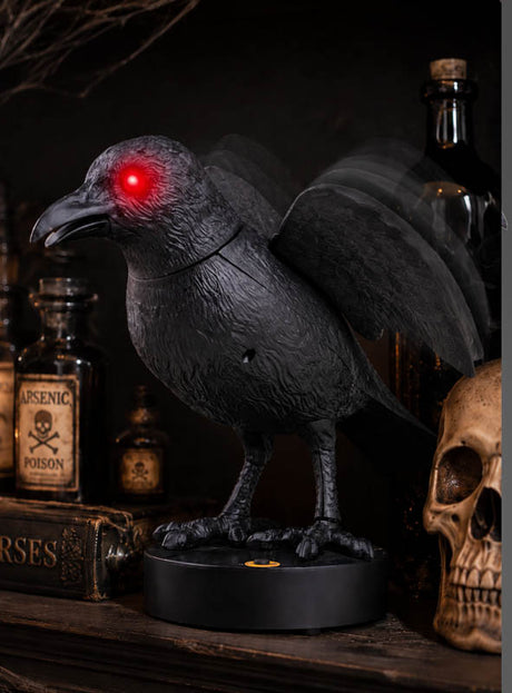 Die „Rabe 24 cm Nevermore, animiert mit LED“ mit leuchtend roten Augen steht auf einem runden Sockel neben alten Flaschen, einem Buch und einem menschlichen Schädel – perfekt als gruselige Halloween-Dekoration.
