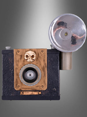 Die „Geister-Fotoapparat 24 cm mit Licht animiert“ im Vintage-Boxkamera-Design mit großem rundem Blitz, Holzfrontplatte und einem kleinen Totenkopf-Ornament über dem Objektiv sorgt für die perfekte gruselige Deko. Vor einem grauen Hintergrund mit Farbverlauf verleiht dieses einzigartige Stück jeder Halloween-Dekoration eine unheimlich besondere Note.