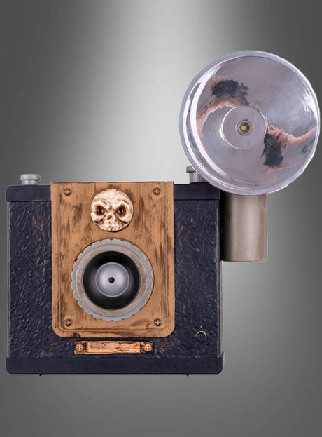 Die „Geister-Fotoapparat 24 cm mit Licht animiert“ im Vintage-Boxkamera-Design mit großem rundem Blitz, Holzfrontplatte und einem kleinen Totenkopf-Ornament über dem Objektiv sorgt für die perfekte gruselige Deko. Vor einem grauen Hintergrund mit Farbverlauf verleiht dieses einzigartige Stück jeder Halloween-Dekoration eine unheimlich besondere Note.