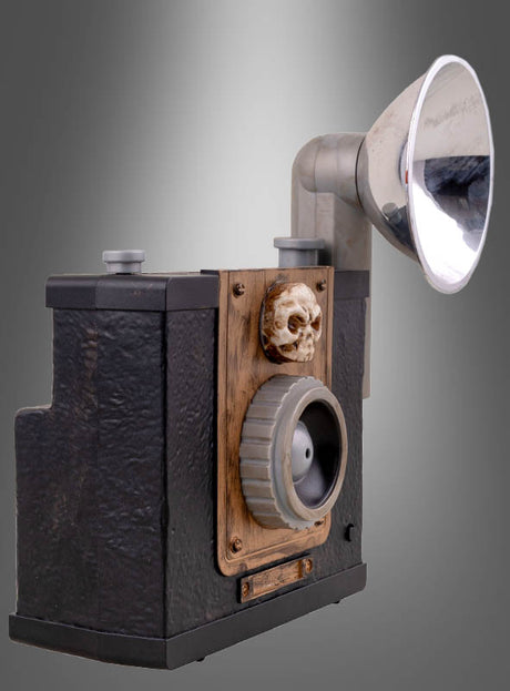 Geister-Kamera, 24 cm, mit Lichteffekt – eine Vintage-Kastenkamera mit großem Blitzaufsatz und kleinen Totenkopf-Details auf der Vorderseite, vor einem grauen Farbverlauf platziert. Perfekt als gruselige Deko oder originelles Highlight für Ihre Halloween-Dekoration!.