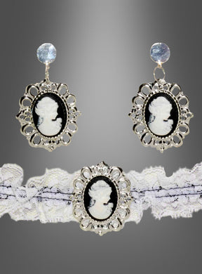 Die silbernen Kameo-Ohrringe und das dazu passende Spitzenhalsband aus dem „Steampunk Schmuck Cameo“-Set zeigen schwarz-weiße Porträts in kunstvollen Rahmen, die die Eleganz des Steampunk-Stils perfekt einfangen – ein ideales Statement-Stück für Gothic-Bräute. Vor einem Hintergrund mit Farbverlauf präsentiert, verbindet dieses Ensemble Vintage-Charme mit modernem Flair.