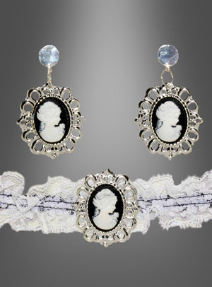 Die silbernen Kameo-Ohrringe und das dazu passende Spitzenhalsband aus dem „Steampunk Schmuck Cameo“-Set zeigen schwarz-weiße Porträts in kunstvollen Rahmen, die die Eleganz des Steampunk-Stils perfekt einfangen – ein ideales Statement-Stück für Gothic-Bräute. Vor einem Hintergrund mit Farbverlauf präsentiert, verbindet dieses Ensemble Vintage-Charme mit modernem Flair.