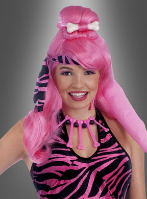 Eine Person, die die „Pinke Perücke mit Knochen Steinzeit“ trägt, dazu ein Kostüm als „Steinzeitfrau“ mit Zebrastreifen und eine rosa Knochenkette, lächelt vor einem grauen Hintergrund mit Farbverlauf.