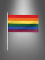 Die Stockfahne „Flagge Regenbogen“ (29 x 17 cm) mit sechs horizontalen Streifen, die an die ikonische Regenbogenfahne erinnern, ist an einem Mast vor einem grauen Hintergrund mit Farbverlauf zu sehen.
