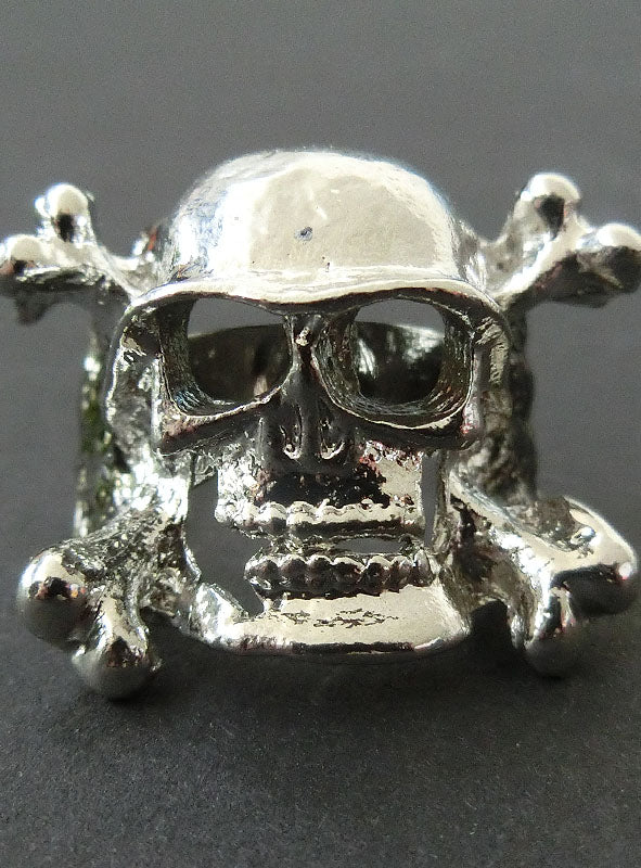 Verstellbarer Totenkopf-Ring aus silbernem Metall, gestaltet als auffälliger Schädel mit gekreuzten Knochen auf dunklem Hintergrund – das perfekte Accessoire, um jedem Rocker-Kostüm oder Biker-Schmuck eine Extraportion Pep zu verleihen.