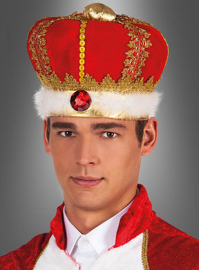 Vor einem grauen Hintergrund steht ein Mann, der eine rot-goldene Königskrone für Erwachsene mit weißem Pelzbesatz und einem roten Edelstein in der Mitte trägt und eine dazu passende rot-weiße königliche Kleidung trägt.