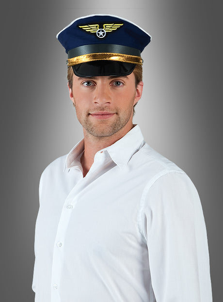 Ein Mann in einem weißen Hemd und einer blauen Pilotenmütze mit der Aufschrift „Kapitän“ steht vor einem grauen Hintergrund mit Farbverlauf und blickt in die Kamera.