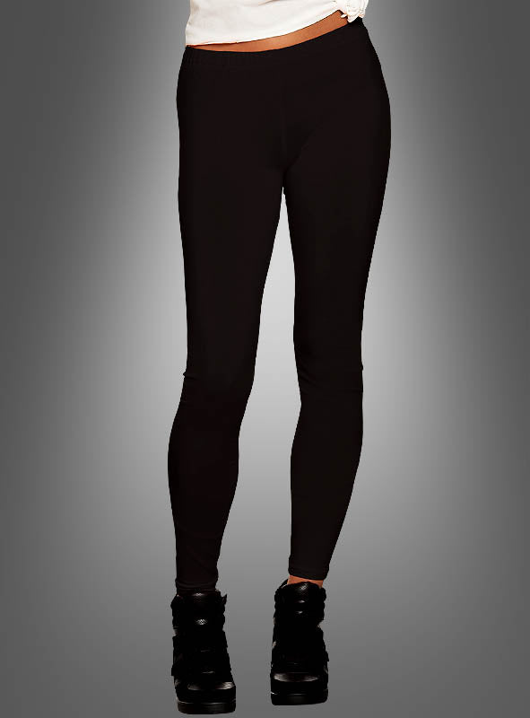 Eine Person ist von der Taille abwärts vor einem grauen Hintergrund mit Farbverlauf zu sehen; sie trägt schwarze Leggings für Damen, schwarze Schuhe und ein weißes Oberteil im 80er-Jahre-Stil.