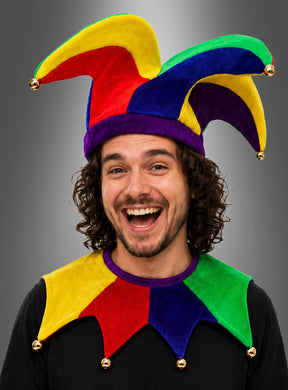 Ein Mann mit lockigem Haar lächelt vor einem grauen Hintergrund mit Farbverlauf, während er das Kostümset „Narrenkappe und Kragen“ (Unisex) trägt.