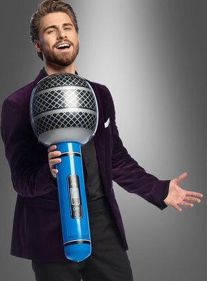 Ein Mann in einem violetten Blazer hält das „Riesiges Mikrofon 76 cm aufblasbar“ vor einem grauen Hintergrund in der Hand und singt hinein – der perfekte Look für jedes Karnevalskostüm.