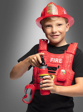 Ein lächelndes Kind, das das Feuerwehrmann-Kostüm-Set für Kinder trägt, bestehend aus einem roten Feuerwehrhelm und einer Weste, hält in einer Hand einen Spielzeugfeuerlöscher, während an seiner Seite eine Schutzbrille hängt.
