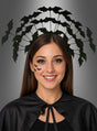 Eine Frau lächelt vor einem grauen Hintergrund. Sie trägt einen schwarzen Umhang, Fledermaus-Gesichtssticker und den Haarreif „Fledermaus-Schwarm“ – ein perfektes Halloween-Kostüm-Accessoire für jede gruselige Feier.