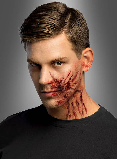 Ein Mann mit gepflegtem braunem Haar und einem schwarzen Hemd trägt realistisch wirkendes Make-up in Form von Kratzspuren, das mit „Spezialeffekt Schminke“ und „Dickes Blut Make-up Halloween“ aufgetragen wurde; rote und dunkle Farbtöne ziehen sich vor grauem Hintergrund von seiner Wange bis zum Hals.