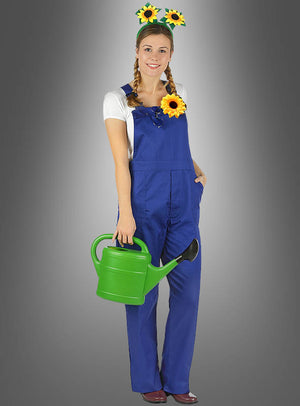 Eine Frau in blauen Latzhosen mit einem Sonnenblumen-Stirnband und einer Anstecknadel, die eine grüne Gießkanne in der Hand hält, steht vor einem grauen Hintergrund mit Farbverlauf – ihr fröhlicher Look wird durch die leuchtende Haarspange „Sonnenblume“ in Gelb-Orange abgerundet, das perfekte Accessoire für eine Hippie-Party.