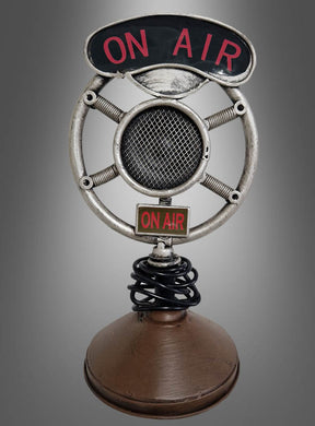 Mikrofon-Dekoration im Stil der 20er Jahre aus Metall mit rundem Metallrahmen und „ON AIR“-Schriftzug oben in der Mitte, auf braunem Sockel vor grauem Hintergrund – perfekt als authentisches Mikrofon im Stil der 20er Jahre oder als Vintage-Mikrofon-Dekoration für Ihre Party im Stil der 20er Jahre.