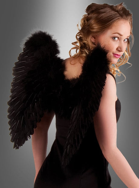 Eine Frau in einem schwarzen Kleid mit lockigem blondem Haar trägt die „Schwarze Flügel 50 x 50 cm – Gefallener Engel“ vor einem grauen Hintergrund mit Farbverlauf und blickt über ihre Schulter. Die auffälligen gotischen Flügel verleihen dem Accessoire für das Karnevalskostüm einen bezaubernden Touch und machen es zu einem wahrhaft faszinierenden Blickfang.
