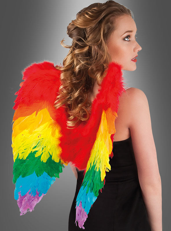 Frau in einem schwarzen Kleid mit lockigem blondem Haar, die große, bunte Regenbogenflügel aus Federn trägt, von hinten gesehen.