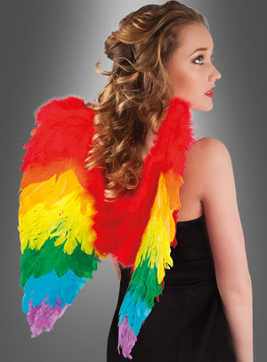 Frau in einem schwarzen Kleid mit lockigem blondem Haar, die große, bunte Regenbogenflügel aus Federn trägt, von hinten gesehen.