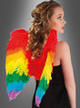 Frau in einem schwarzen Kleid mit lockigem blondem Haar, die große, bunte Regenbogenflügel aus Federn trägt, von hinten gesehen.