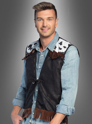 Ein Mann in einem Jeanshemd und der „Cowboy-Weste für Herren“ – mit schwarzen Einsätzen, Schultern im Kuhmuster und braunen Fransen – steht lächelnd vor einem grauen Hintergrund mit Farbverlauf. Damit ist diese Weste die perfekte Wahl für Ihre nächste Wild-West-Mottoparty oder als auffälliges Karnevalsaccessoire.