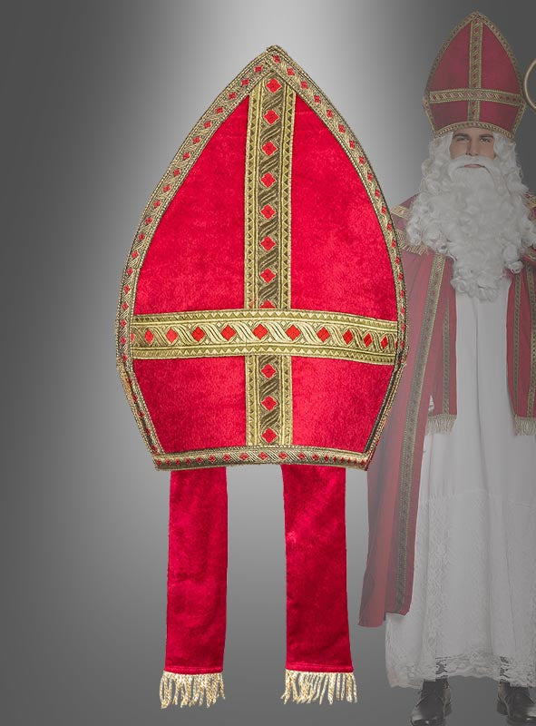 Im Mittelpunkt ist eine edle Rote Mitra-Bischofsmütze mit langen, herabhängenden Laschen zu sehen, im Hintergrund ist teilweise eine Person in einem Sankt-Nikolaus-Kostüm zu erkennen.