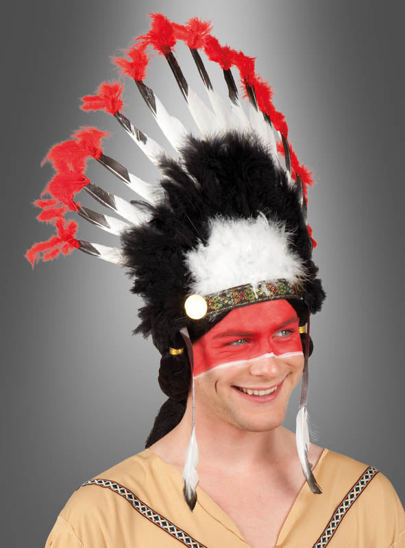 Auf dem Bild ist eine Person vor grauem Hintergrund zu sehen, die den „Federschmuck Indianer Häuptling“ trägt, komplett mit Federkopfschmuck, roter Gesichtsbemalung und einem hellbraunen Kostüm, das an einen Indianerhäuptling erinnert.