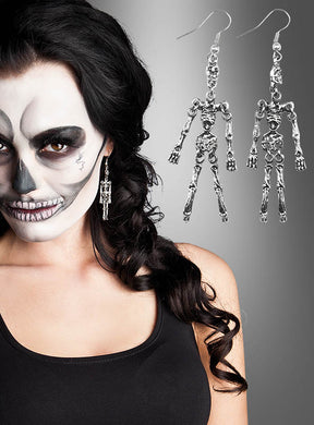 Eine Frau mit Skelett-Gesichtsbemalung trägt ein schwarzes Trägertop und präsentiert den „Ohrringe Skelett“-Halloween-Schmuck – das perfekte Accessoire für Halloween. Rechts ist eine vergrößerte Ansicht der „Ohrringe Skelett“ vor einem grauen Hintergrund mit Farbverlauf zu sehen.