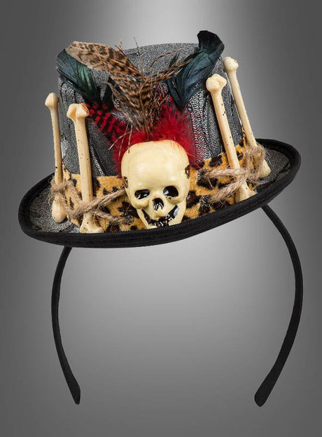 Graues Stirnband im Zylinder-Stil, der „Minizylinder mit Totenkopf Voodoo“, verziert mit Kunstknochen, einem Plastikschädel, Stoff mit Tiermuster, Federn und Schnur vor einem grauen Farbverlaufshintergrund – perfekt als Accessoire für dein Voodoo-Priesterin-Kostüm oder als einzigartiges Halloween-Zubehör.