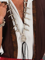 Eine Person, die ein braun-weißes Hemd trägt, dazu eine Lange Totenkopf-Halskette mit Zähnen, bestehend aus einem Totenkopf-Anhänger und einem passenden Armband – das perfekte Accessoire für ein Piratenkostüm.