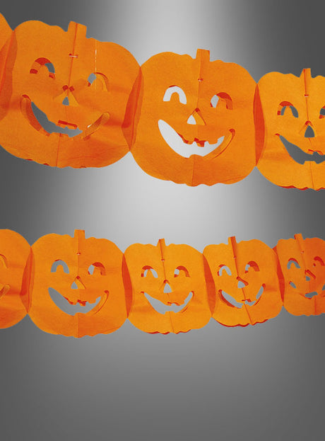 Kürbis-Papiergirlande zu Halloween aus orangefarbenem Papier mit wiederkehrenden Jack-o-Lantern-Motiven, präsentiert vor einem neutral-grauen Hintergrund – ideal als auffällige Herbstdekoration für deine Halloween-Party.