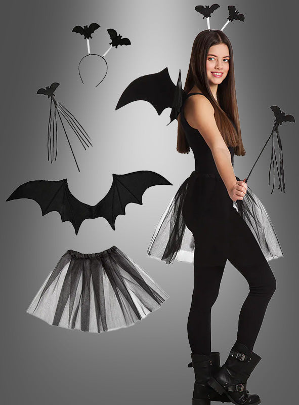 Eine Frau trägt das „Fledermaus“-Kostüm-Set, bestehend aus schwarzen Fledermausflügeln, einem Tüllrock, einem mit Fledermäusen verzierten Stirnband und einem Fledermaus-Zauberstab – ideal für jedes Halloween-Kostüm; jedes Teil ist einzeln vor einem grauen Hintergrund abgebildet.