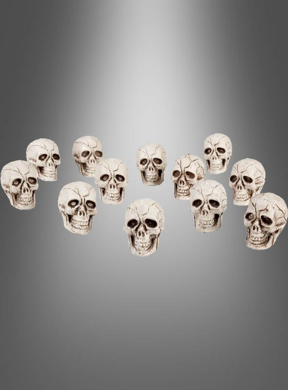 Zwölf Totenkopf-Repliken im Format 4 x 3 cm (Produkt: 12 Totenköpfe, 4 x 3 cm), halbkreisförmig angeordnet auf einem grau abgestuften Hintergrund – ideal für Ihre Halloween-Dekoration oder jedes Bastelprojekt.