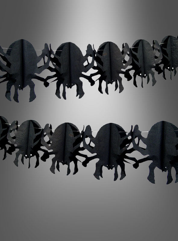 Zwei Reihen der „Spinnengirlande 4 Meter“ – schwarze Papiergirlanden in Spinnenform – sind vor einem grauen Hintergrund mit Farbverlauf angeordnet und eignen sich somit perfekt als Partydekoration für Ihre nächste Halloween-Party.