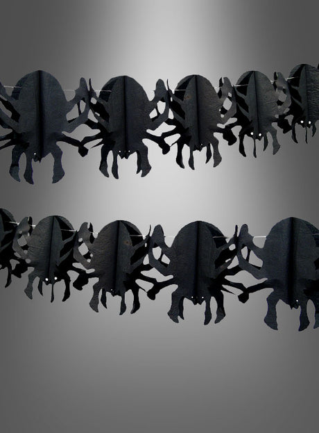 Zwei Reihen der „Spinnengirlande 4 Meter“ – schwarze Papiergirlanden in Spinnenform – sind vor einem grauen Hintergrund mit Farbverlauf angeordnet und eignen sich somit perfekt als Partydekoration für Ihre nächste Halloween-Party.