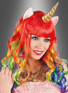 Eine Person lächelt vor einem grauen Hintergrund und trägt die „Einhorn-Perücke für Damen“ – eine leuchtend rote Perücke in Regenbogenfarben mit einem Einhornhorn und weißen Ohren –, die den Zauber eines idealen Einhornkostüms perfekt einfängt.