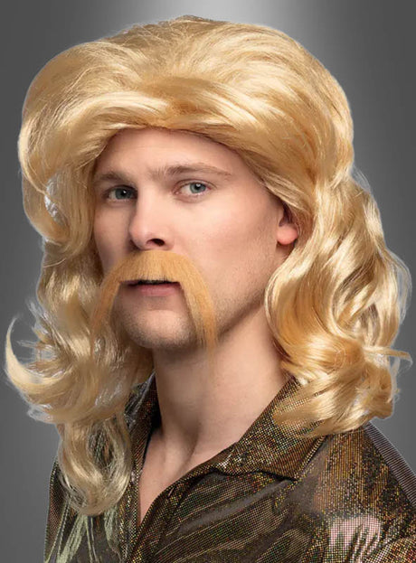 Eine Person, die die blonde Perücke „Barry mit Bart“ trägt und ein glänzendes Metallic-Shirt im Langhaar-Stil der 70er Jahre angezogen hat, posiert vor einem grauen Hintergrund.