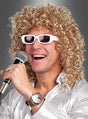 Ein Mann, der die „Blonde Lockenperücke Herren mit Brille“ trägt, lächelt, während er ein Mikrofon in der Hand hält, und scheint vor einem grauen Hintergrund zu singen oder aufzutreten; er trägt eine weiße Sonnenbrille und ein glänzendes Hemd.